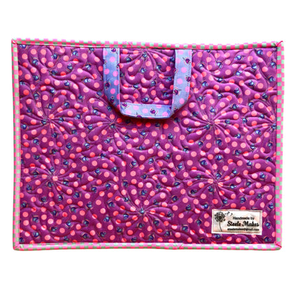 Pink and purple patterned bag with a visible brand label on a white background needlepoint project bag quilted daisy