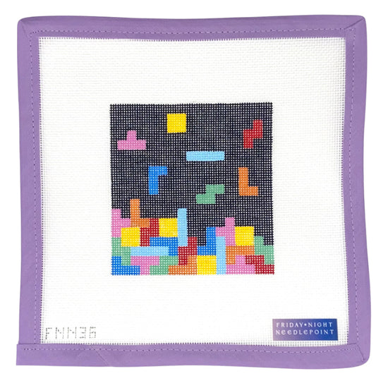 Framed needlepoint with colorful geometric design on a white background